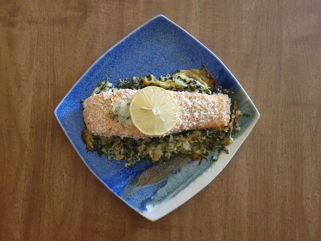 Finished meal: the stuffed salmon Florentine gratin has been carefully scooped onto a blue square plate.