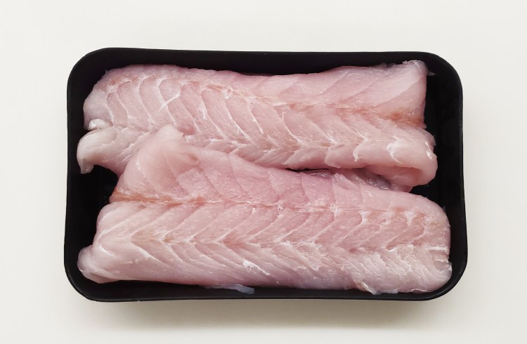 Two pieces of pink corvina lay side by side in a black display tray in alternate directions.