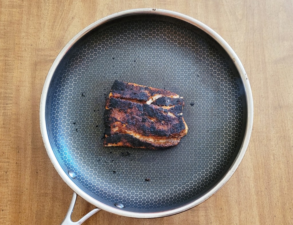 A full picture of perfectly blackened corvina in the frying pan.